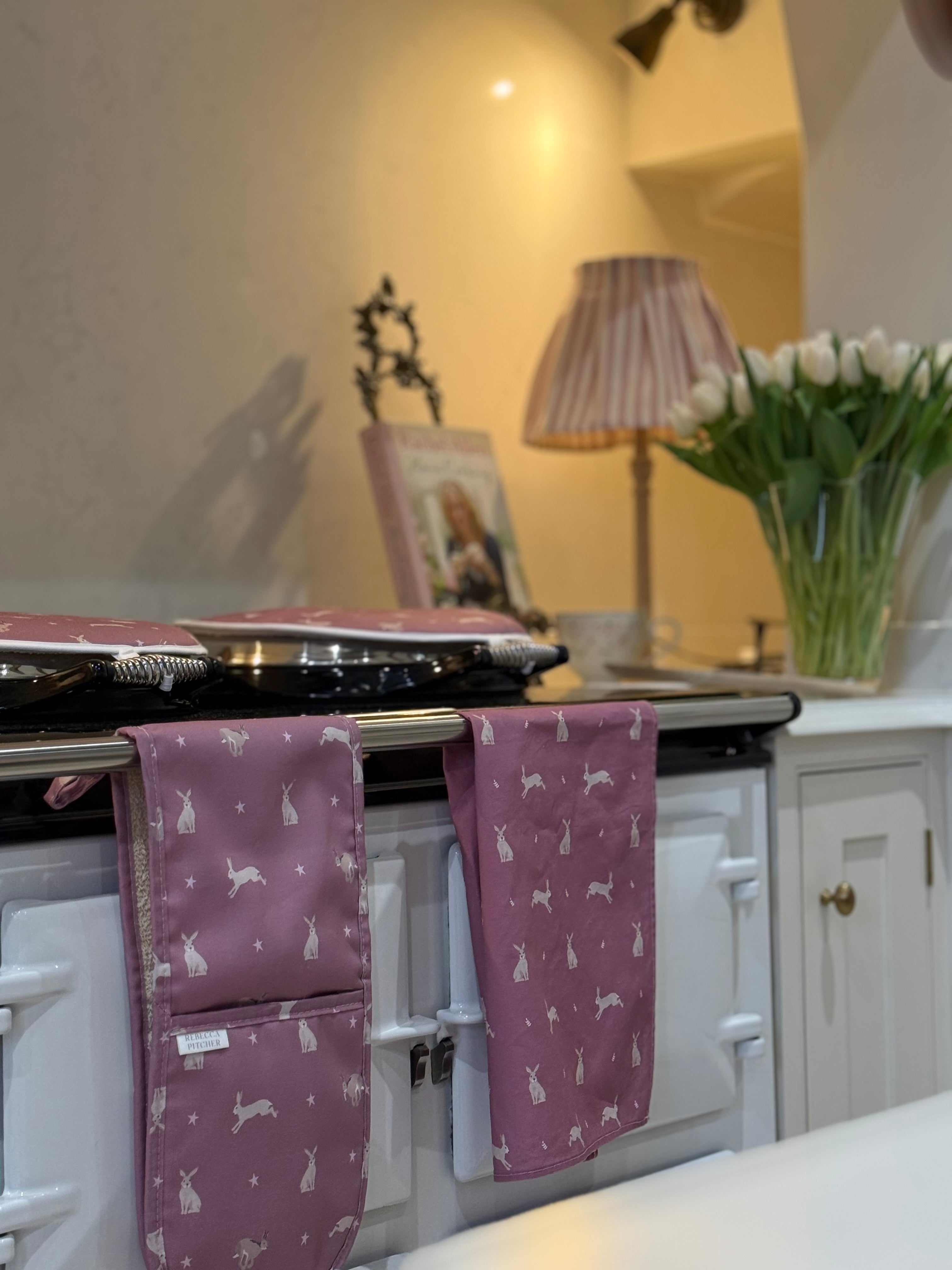 Pink hare oven gloves, tea towel and hob covers in a country kitchen