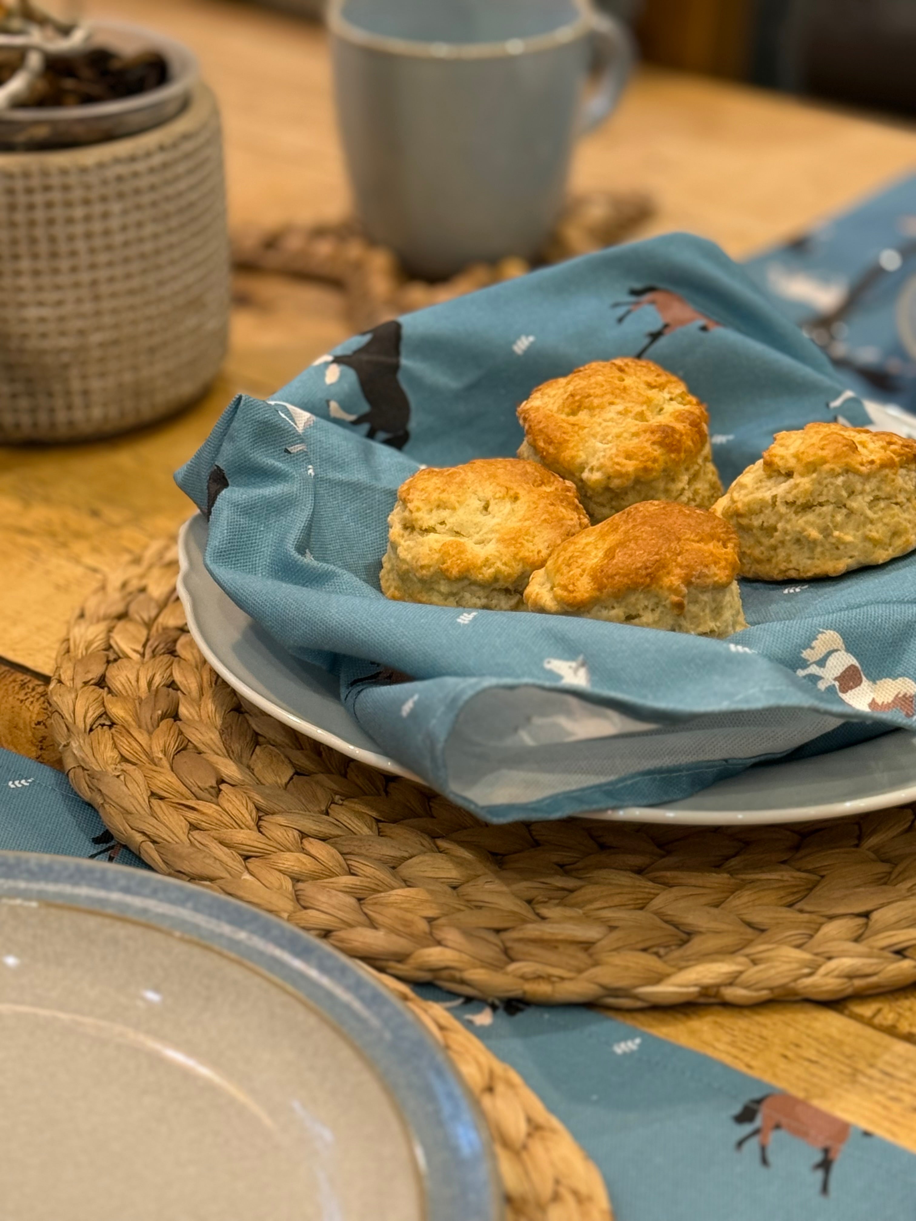 scones on a blue cotton horse print napkin with a matching placemat and mug in the background