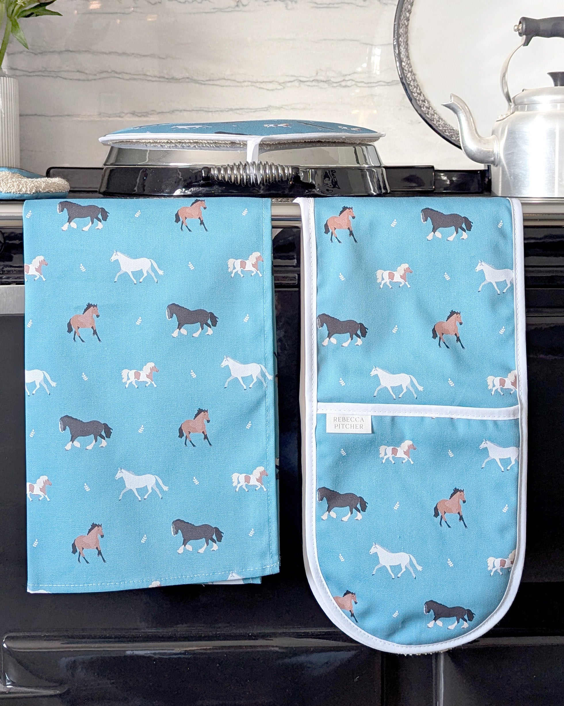 Set of kitchen towel and oven gloves with horse pattern on a stove
