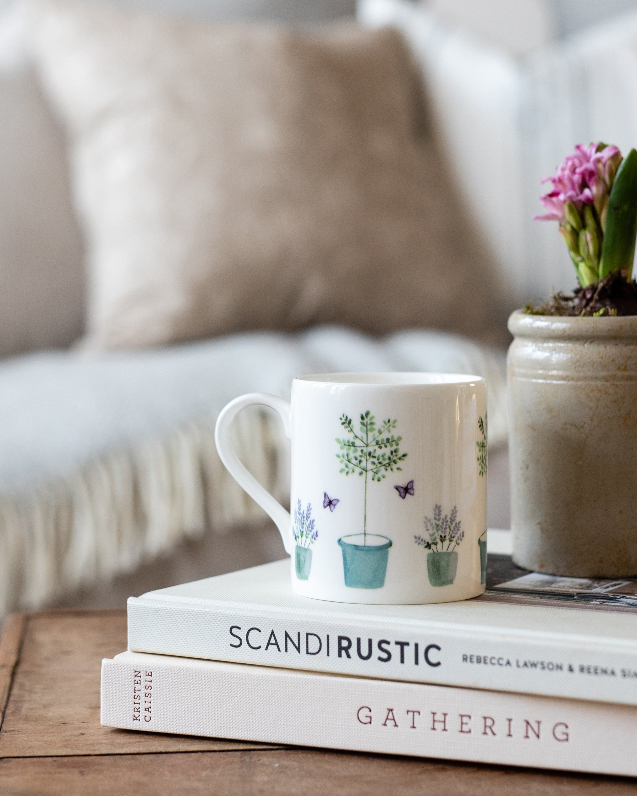 China mug with plant designs on a stack of books with a blurred background