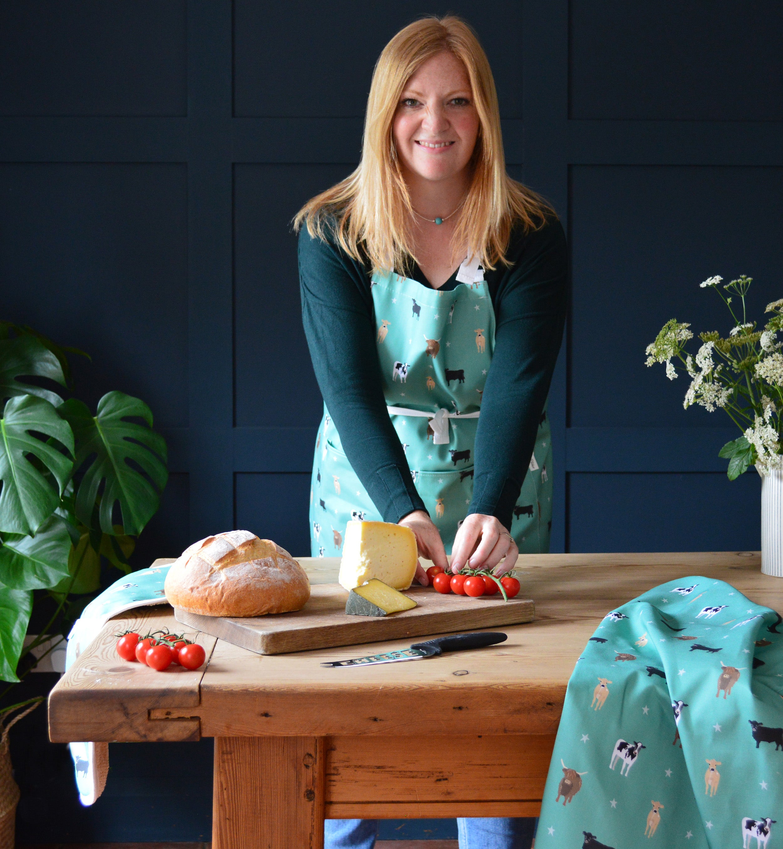 Rebecca Pitcher Green Cow Print kitchen apron, tea towel and oven gloves at the kitchen table