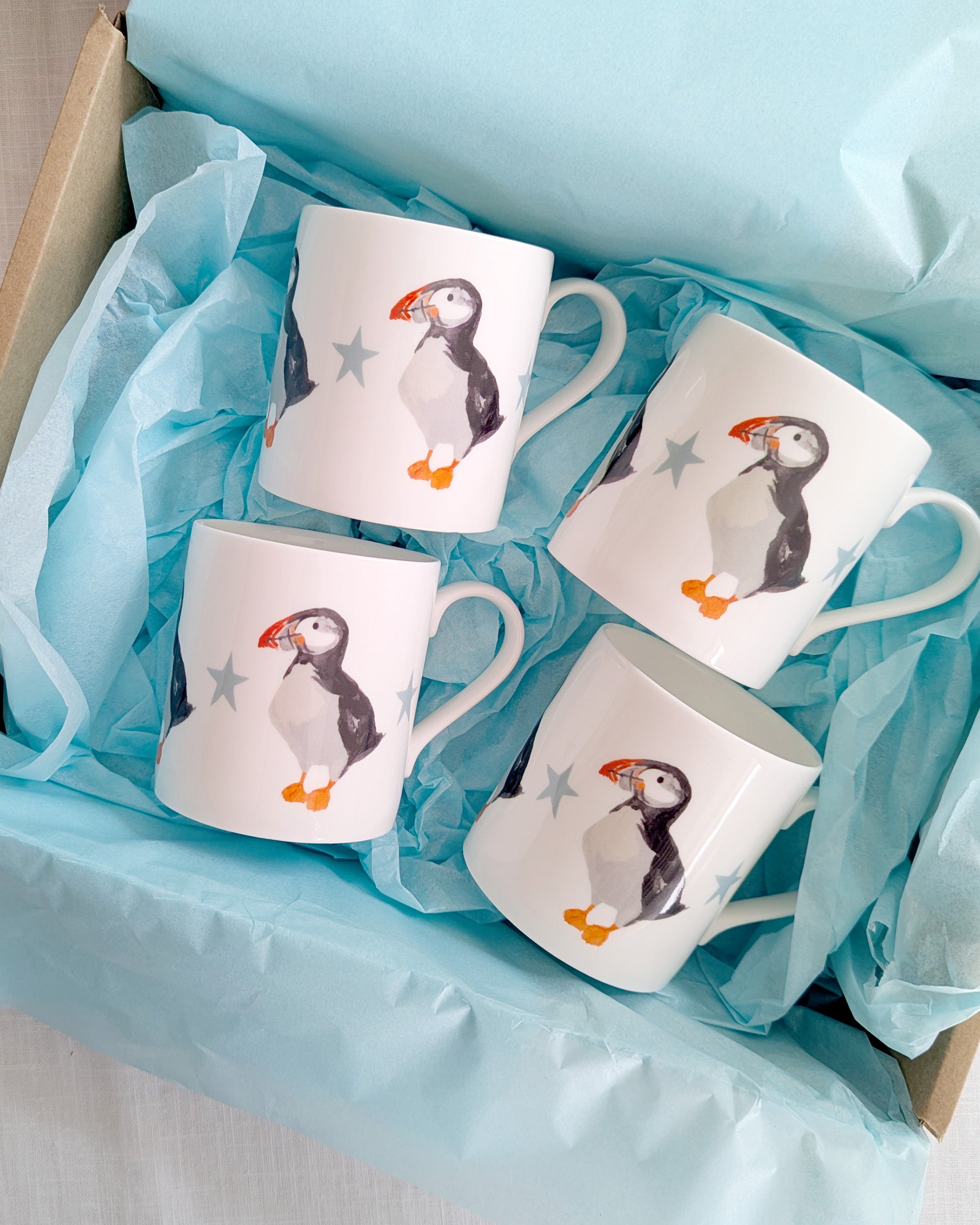 Set of four mugs with puffin designs in a box with blue tissue paper