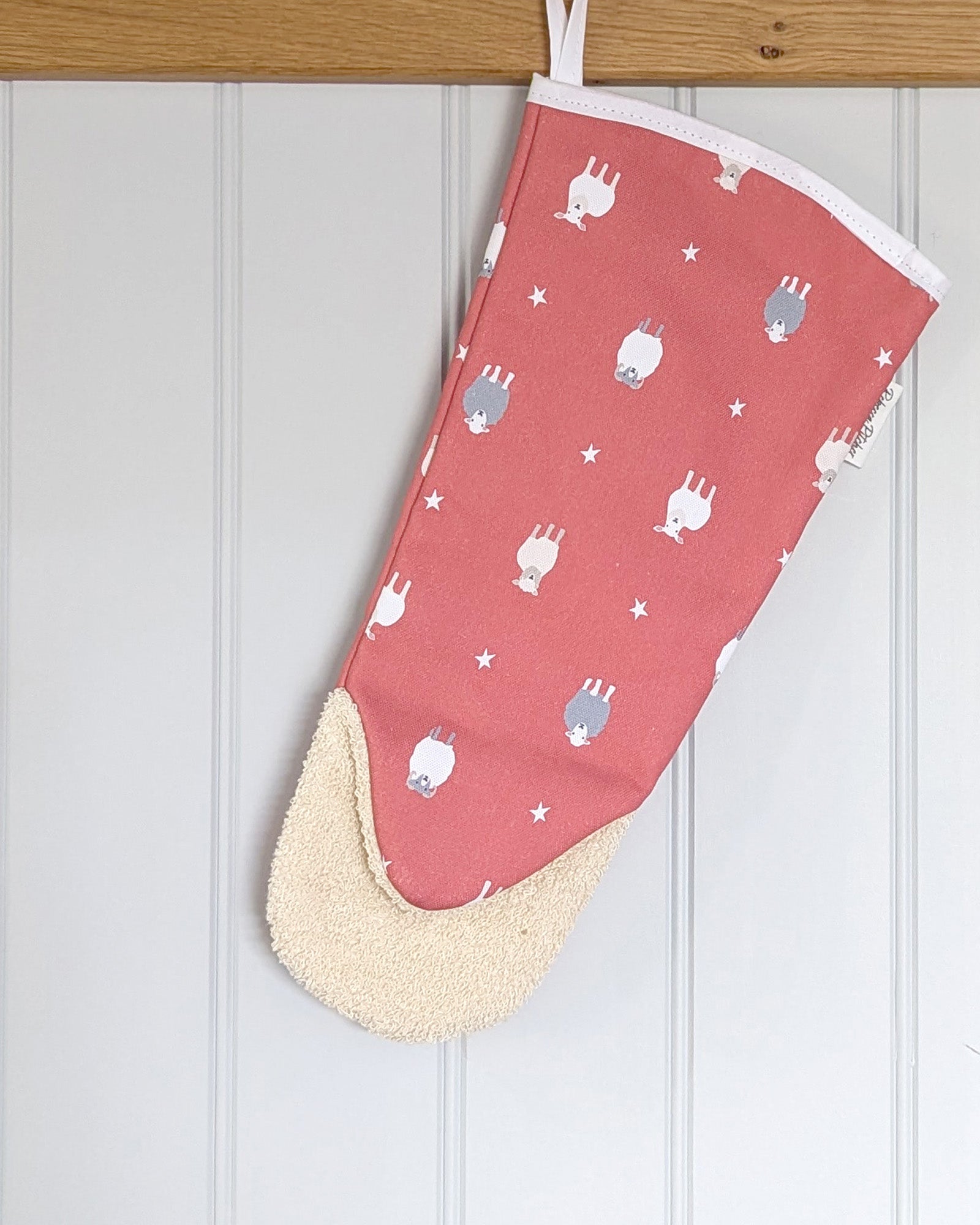 Red oven mitt with sheep patterns hanging in a kitchen