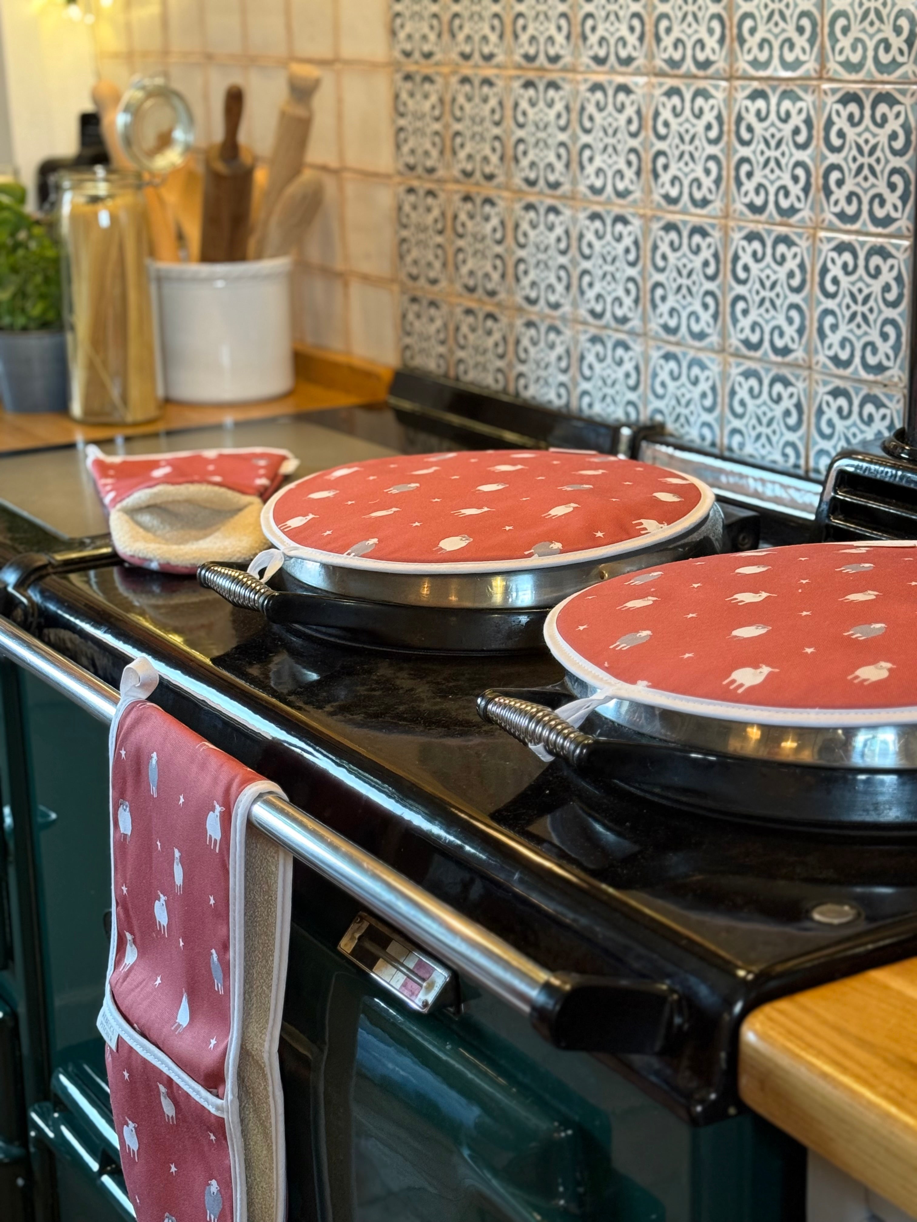 Country kitchen stovetop with red and white sheep patterned hob covers and oven gloves