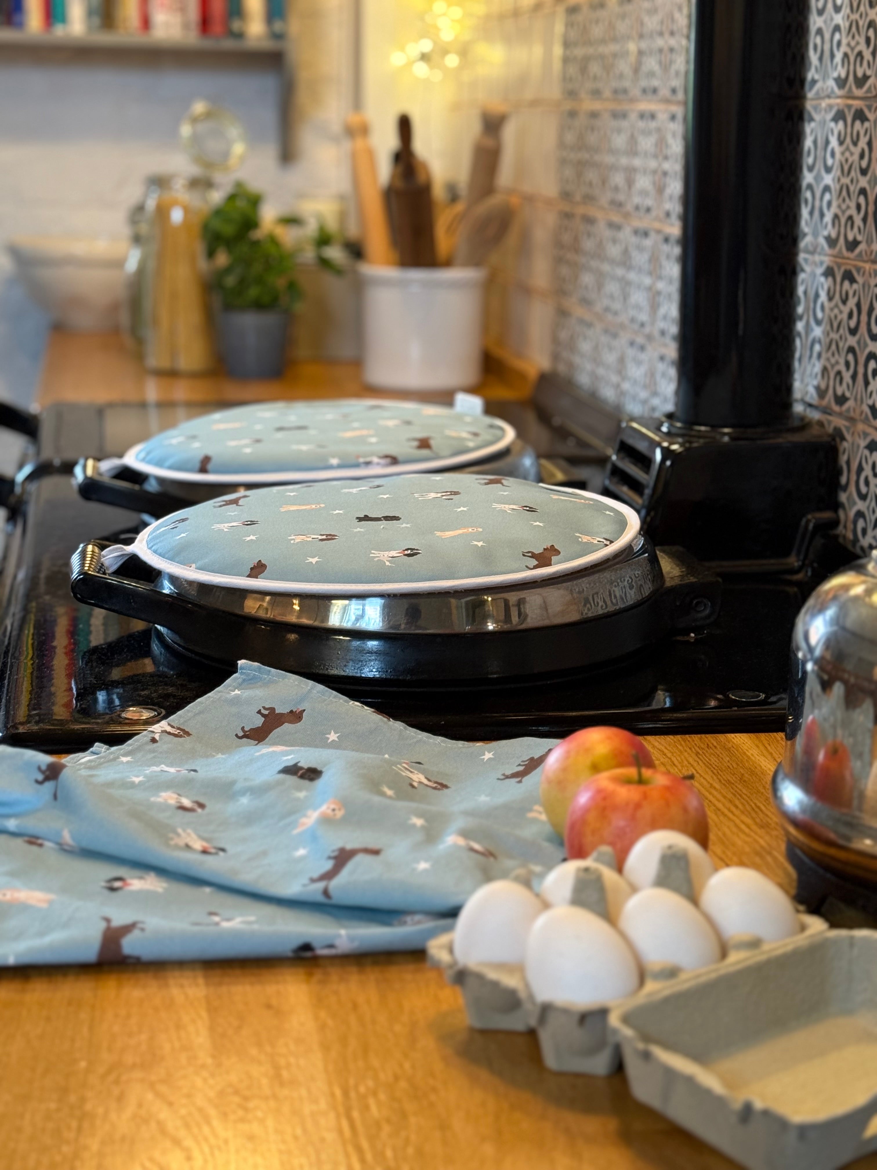 Stovetop with spaniel dog patterned hob covers and tea towel on a kitchen counter